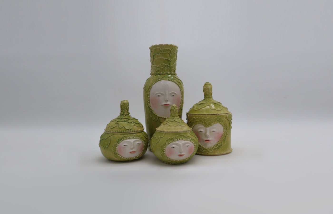 a family of cabbage-people jars and a vase
